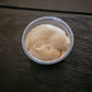 Top view of a 2 oz. container of peanut butter dip on a dark surface. Made in the kitchen of Nystrom Orchard in Worthington Minnesota.