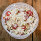 Container of chicken salad with grapes chicken celery, dill, poppy seeds on a wooden surface. Made in the kitchen of Nystrom Orchard in Worthington Minnesota.