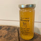Pure Natural Honey in a 12 oz jar on a wooden surface with a white background. Sold by Nystrom Orchard in Worthington Minnesota.
