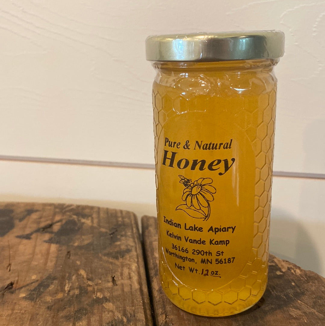 Pure Natural Honey in a 12 oz jar on a wooden surface with a white background. Sold by Nystrom Orchard in Worthington Minnesota.